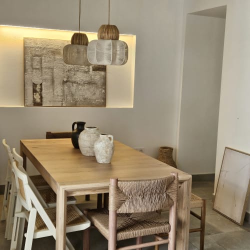 Comedor moderno con mesa de madera, sillas tejidas, lámparas colgantes y arte rústico en la pared del apartamento Casa De La Cruz Vejer