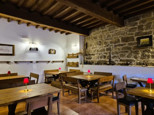 Comedor rústico en Aldea Rural Pazos De Arenteiro con vigas de madera, muros de piedra y mesas iluminadas con velas