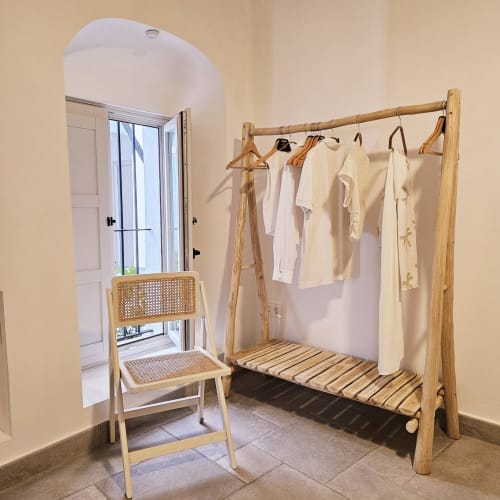 Perchero de madera con prendas blancas y perchas en el apartamento Casa De La Cruz Vejer, Vejer de la Frontera