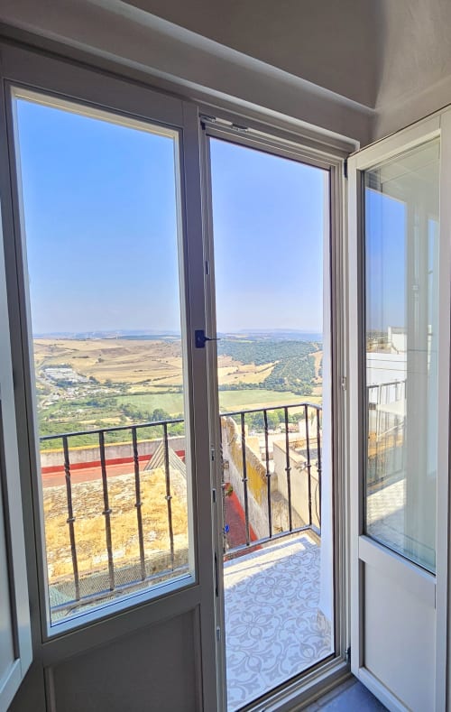 Puertas de cristal abiertas en el balcón del apartamento Casa De La Cruz Vejer con vistas al campo y los verdes valles de Vejer de la Frontera