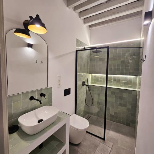 Baño moderno en apartamento Casa De La Cruz con ducha de azulejos verdes, lavabo blanco, inodoro y lámpara negra de arco