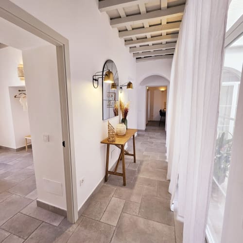 Pasillo luminoso con mesa de madera y lámparas colgantes de latón en Casa De La Cruz Vejer, Vejer de la Frontera
