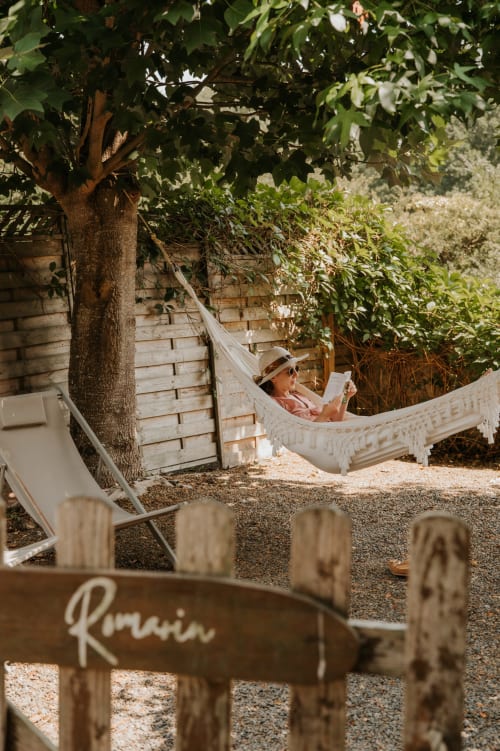 Un invité se détend dans un hamac au gîte Les Granges De Pil Bara à Langoat, France, entouré d'un jardin luxuriant