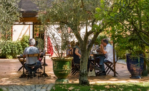 Des clients se détendent dans la cour-jardin de l'Auberge du Parc à Correns, entourés de verdure luxuriante