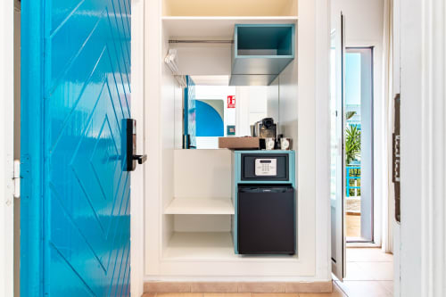 Compacta cocineta de hotel en Smart Hotel Cabo Sur con minibar, microondas y puerta turquesa en Mojácar