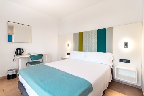 Moderno dormitorio doble en Smart Hotel Cabo Sur de Mojácar con ropa de cama blanca, detalles turquesas y mobiliario contemporáneo