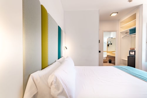 Moderna habitación doble en Smart Hotel Cabo Sur en Mojácar con cabecero colorido, ropa de cama blanca y baño privado visible