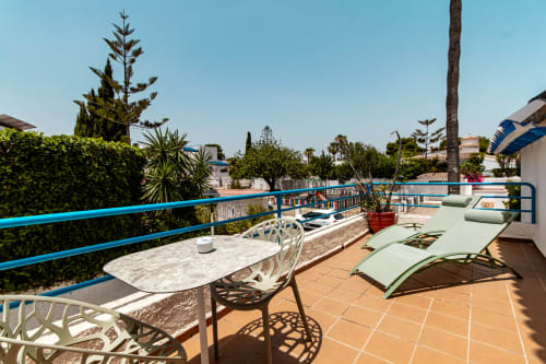 Terraza soleada del Smart Hotel Cabo Sur en Mojácar con barandilla azul, tumbonas, mesa de comedor y palmeras con vistas