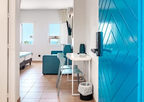 Habitación Doble Superior del Smart Hotel Cabo Sur con vistas al océano, escritorio, zona de estar y puerta azul en Mojácar