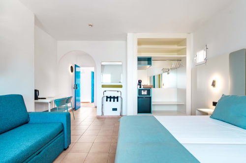 Luminosa habitación moderna en Smart Hotel Cabo Sur, Mojácar, con sofá turquesa, cama, cocina y vistas al océano
