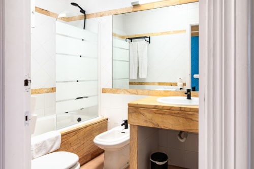 Baño moderno del Smart Hotel Cabo Sur en Mojácar con tocador de madera, ducha de cristal y accesorios blancos