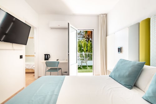 Luminosa habitación doble con terraza en Smart Hotel Cabo Sur de Mojácar, con almohadas azules, TV y vistas al jardín