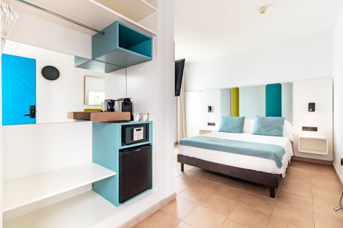 Habitación moderna del Smart Hotel Cabo Sur en Mojácar con cocineta turquesa, cama queen y decoración contemporánea