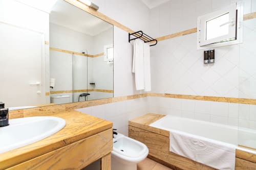 Baño moderno en Smart Hotel Cabo Sur, Mojácar con mueble de madera, azulejos blancos, bañera y cabina de ducha