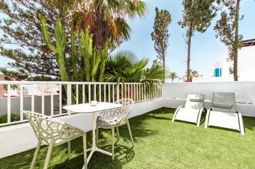 Amplia terraza con césped artificial, muebles blancos y plantas tropicales en Smart Hotel Cabo Sur, Mojácar