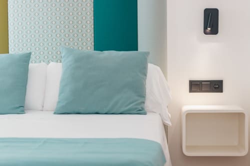 Habitación moderna del Smart Hotel Cabo Sur en Mojácar con almohadas turquesas, ropa de cama blanca y apliques contemporáneos