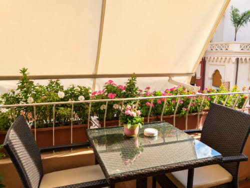 Terrazza soleggiata della B&B Pellicano Guest House con piante fiorite, tavolo da pranzo e vista sulla città di Reggio Calabria