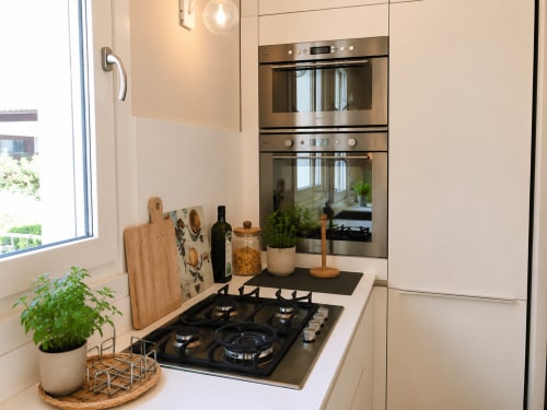 Cucina moderna con piano cottura a gas, elettrodomestici in acciaio inossidabile e mobili bianchi presso Pellicano Guest House a Reggio Calabria
