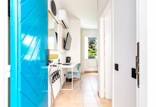 Luminosa habitación moderna en Smart Hotel Cabo Sur con puerta azul vibrante, escritorio, cocina y acceso a terraza en Mojácar