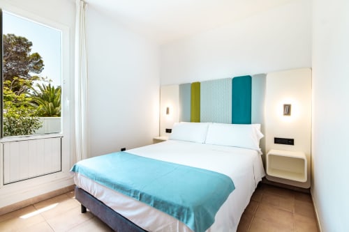 Luminosa habitación moderna del Smart Hotel Cabo Sur, Mojácar con acentos turquesas, ropa de cama blanca y vistas a la terraza