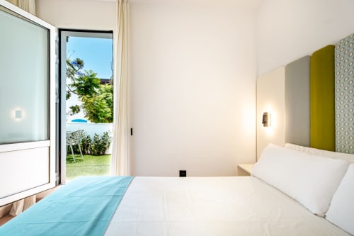 Moderno dormitorio doble en Smart Hotel Cabo Sur, Mojácar, con acceso a terraza, cabecero verde y vistas a la piscina del jardín