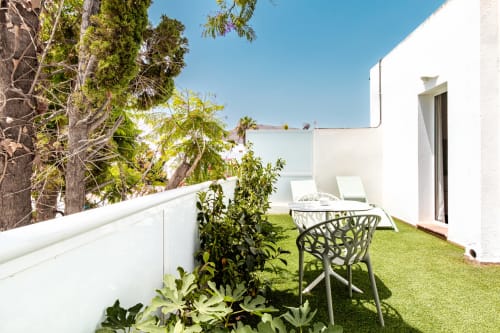 Soleada terraza del Smart Hotel Cabo Sur en Mojácar con mobiliario blanco, césped artificial y vistas a las montañas