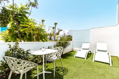 Soleada terraza del Smart Hotel Cabo Sur en Mojácar con tumbonas blancas, mesa de comedor y césped artificial verde exuberante
