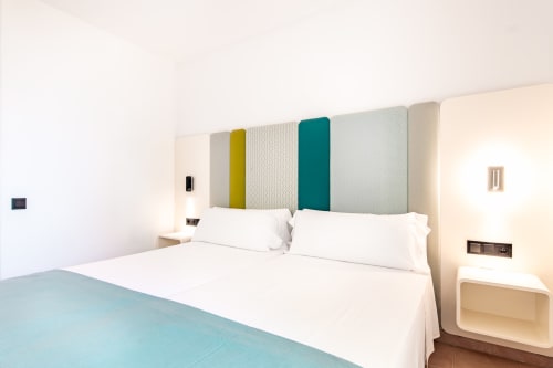 Moderna habitación doble en Smart Hotel Cabo Sur, Mojácar, con cabecero colorido y ropa de cama blanca
