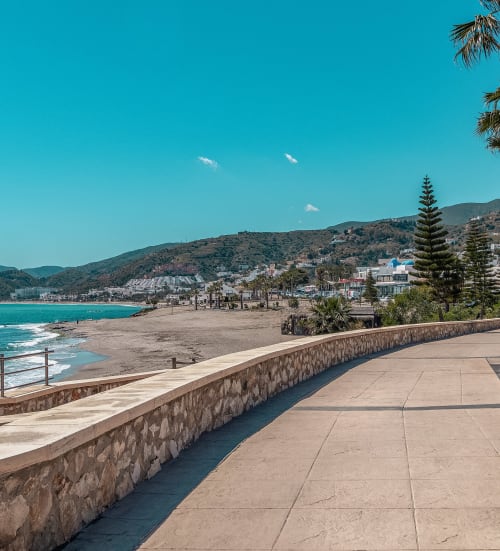 Paseo frente al mar del Smart Hotel Cabo Sur en Mojácar con aguas turquesas, playa de arena y vistas del pueblo en la ladera