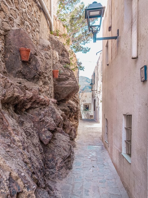 Estrecho callejón de piedra en Mojácar con macetas de barro, farolillo y casas encaladas en Smart Hotel Cabo Sur