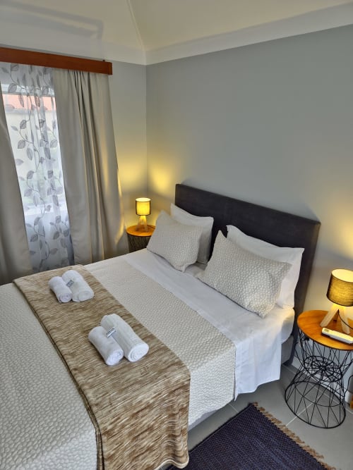 Quarto moderno do Refúgio do Nevoeiro com camas de casal, luminárias amarelas e cortinas estampadas em Porto Moniz
