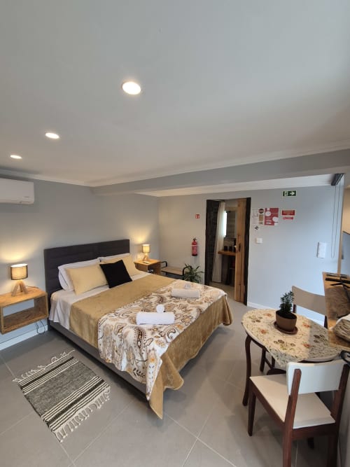 Quarto moderno do Refúgio do Nevoeiro em Porto Moniz com cama queen, mesas de cabeceira em madeira e mobiliário contemporâneo