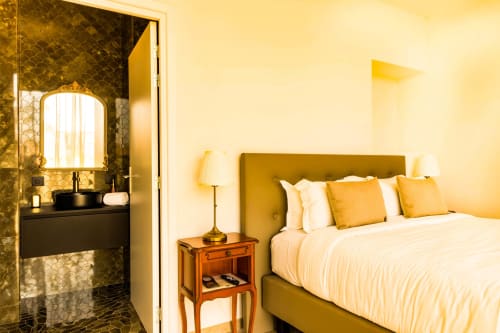 Luxury hotel bedroom at Hôtel Villa Martini in Ajaccio with olive-green upholstered bed, white linens, yellow pillows,