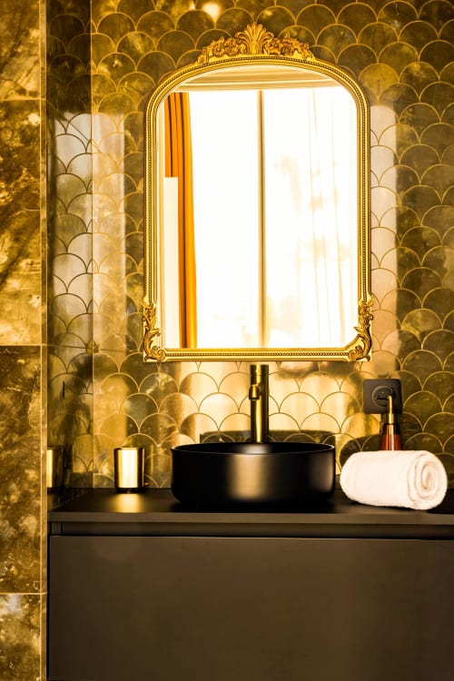 Luxury bathroom vanity at Hôtel Villa Martini Ajaccio with black round sink, ornate gold mirror, and scalloped tile