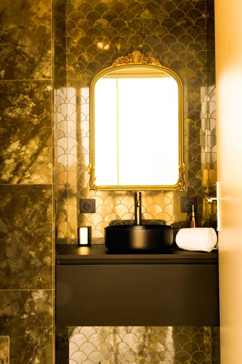 Luxurious bathroom vanity at Hôtel Villa Martini Ajaccio with ornate golden mirror, black basin sink, and scale-pattern wall
