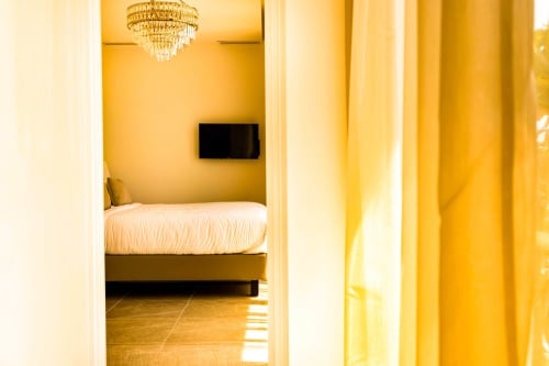 Bright yellow bedroom at Hôtel Villa Martini in Ajaccio with bed, flat-screen TV, and chandelier lighting