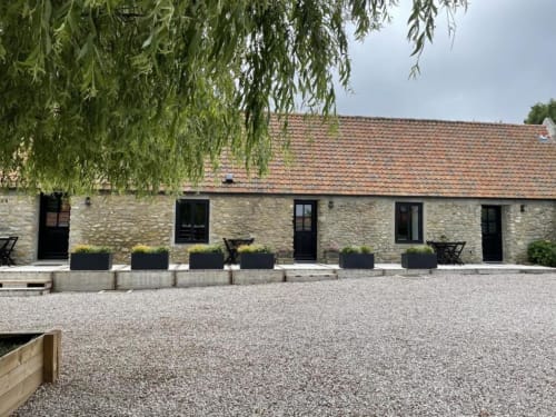 Maison de pierre avec toiture en terre cuite aux Gîtes du Grand Saule à Tardinghen, portes noires et cour aménagée