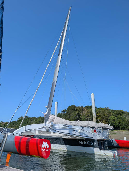 Catamaran moderne aux voiles rouges avec branding MACSF amarré près de Runan, France pour le Gîte de Ker Huon