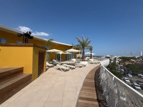 Terrasse sur le toit d'Agde Luxury Loc avec transats, parasols, palmier et vue sur la ville