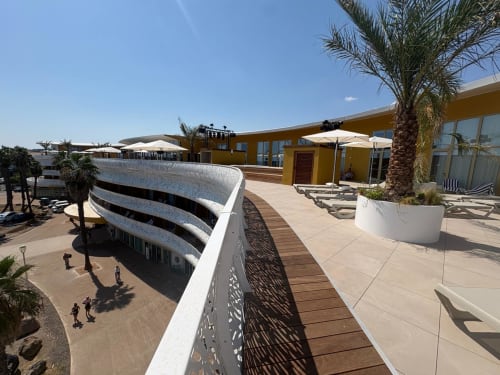 Vue sur la terrasse à Agde Luxury Loc avec bâtiment jaune, palmiers, transats et accès à la plage à Cap d'Agde, France