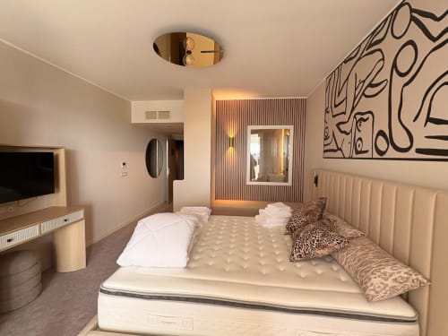 Chambre moderne à Vibes Infinity, Agde Luxury Loc, avec lit spacieux, TV écran plat et œuvres d'art contemporain.