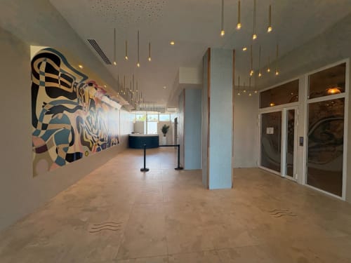 Entrée moderne du lobby d'Agde Luxury Loc avec œuvres d'art colorées, luminaires suspendus et réception à Le Cap d'Agde