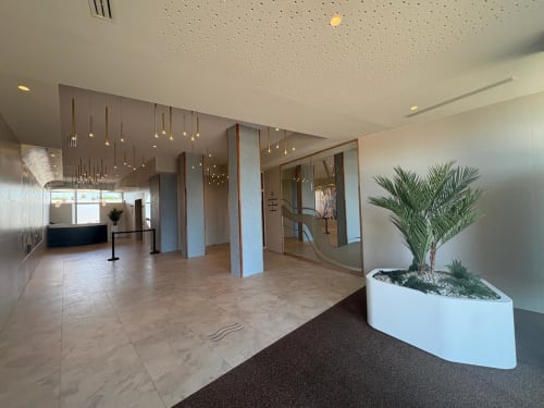 Élégant hall d'accueil d'Agde Luxury Loc à Cap d'Agde avec sols en marbre, plante en pot, luminaires suspendus et surfaces vitrées