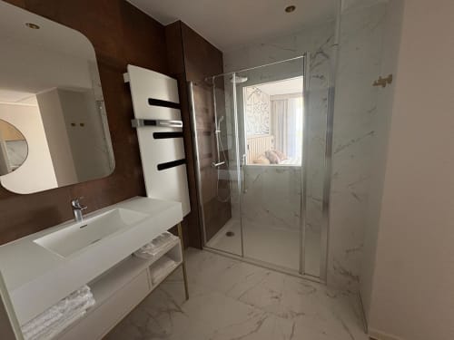 Salle de bain moderne de l'appartement Vibes Infinity à Agde Luxury Loc avec marbre, lavabo blanc, radiateur sèche-serviettes et
