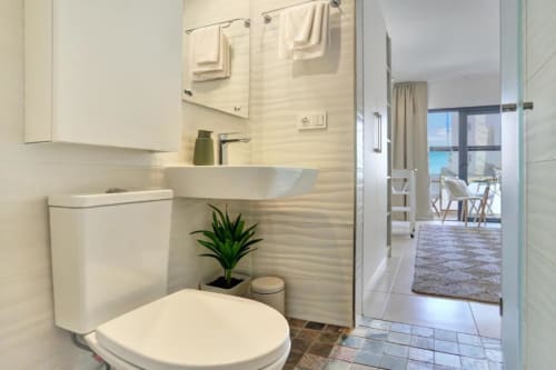 Baño moderno en loft de Kamalahouse, Corralejo con lavabo blanco, inodoro y acceso a vistas al mar