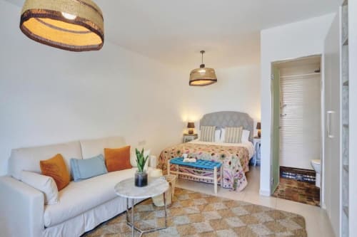 Luminoso salón con sofá color crema, cama queen, lámparas colgantes y vistas al mar en Corralejo