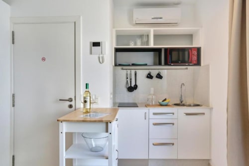 Pequeña cocina en apartamento Kamalahouse SL, Corralejo con gabinetes blancos, encimera de madera, fregadero de acero inoxidable y