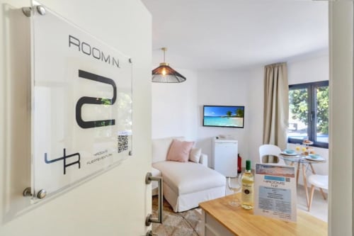 Interior moderno del apartamento en Kamalahouse, Corralejo, con vistas al mar, sofá blanco, comedor y TV de pantalla plana