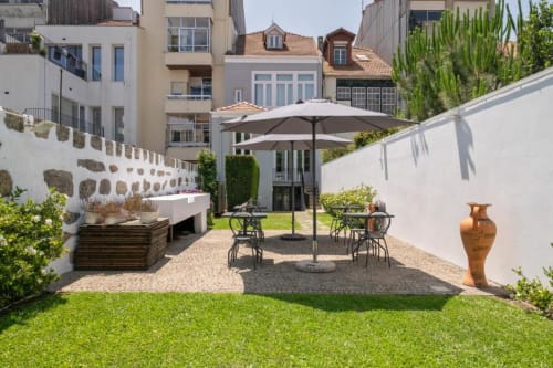 Pátio charmoso da Oporto Comfort Charming House em Cedofeita com área de refeições, guarda-sóis, jardim e vista para o Porto.