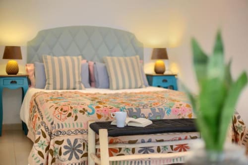 Dormitorio elegante en el apartamento Kamalahouse SL de Corralejo con cabecero azul, almohadas rayas, ropa de cama colorida y vistas al mar